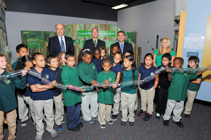 Children cutting a ribbon made of recycled water bottles to open new energy-conservation exhibits at the CRRA Trash Museum.