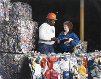 Two workers inspect bales of cans and bottles
